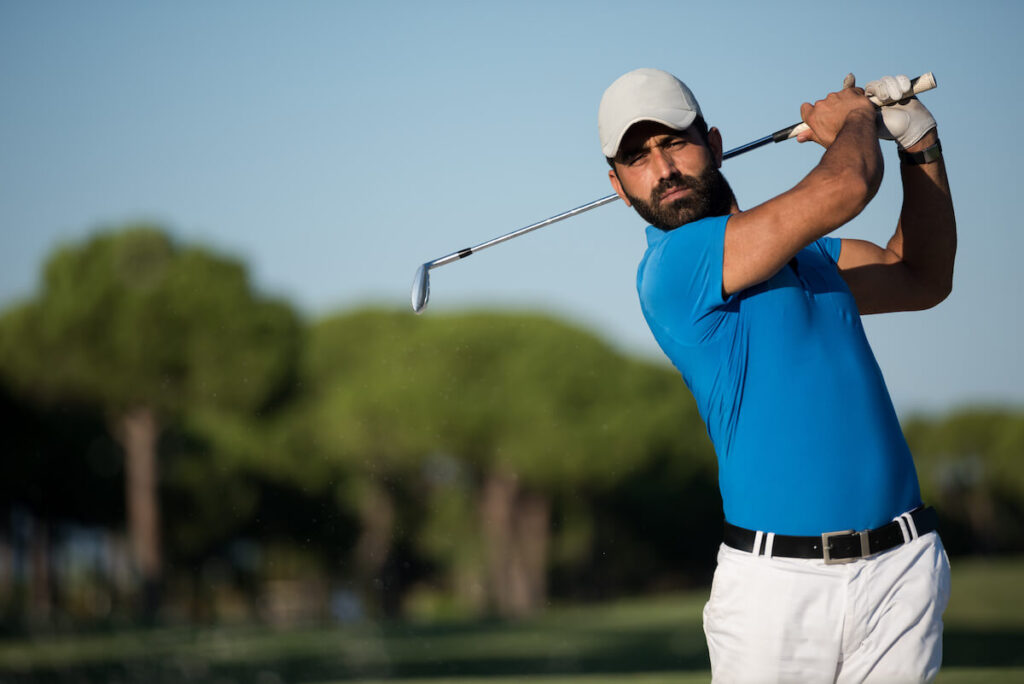 Golf swing sequence: A man holds his club after his follow-through