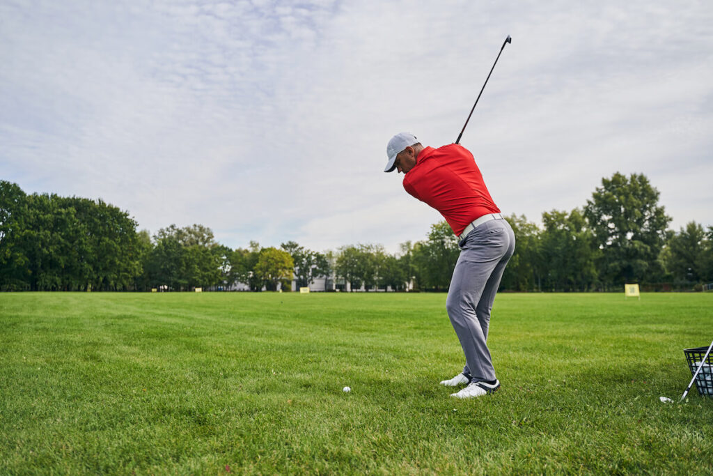 A man in the middle of his backswing on a golf course
