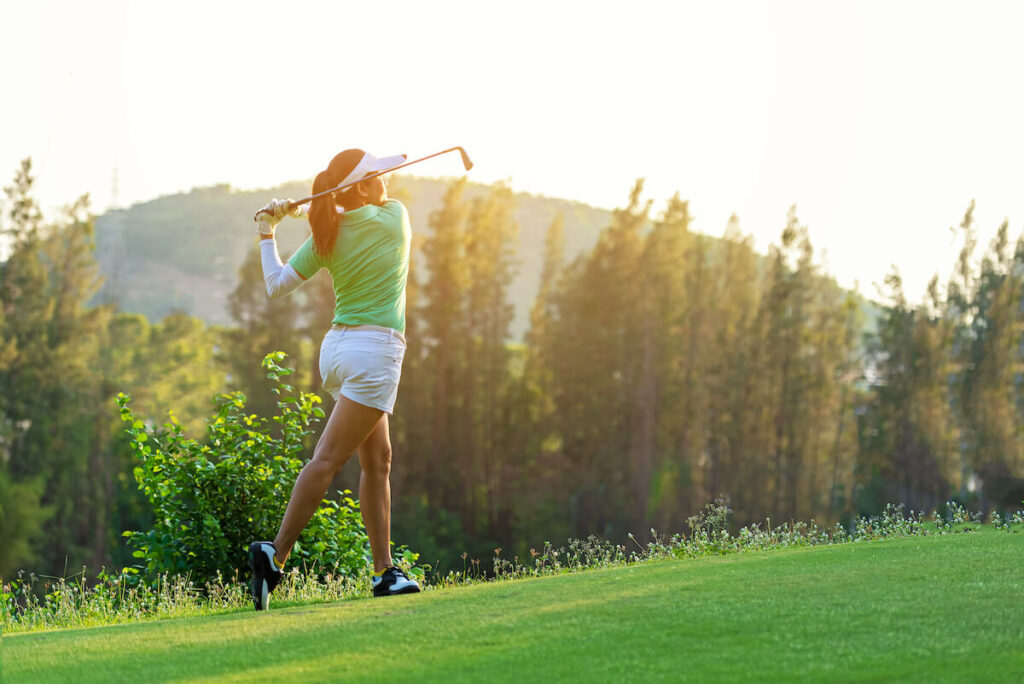 A woman finishes her golf swing