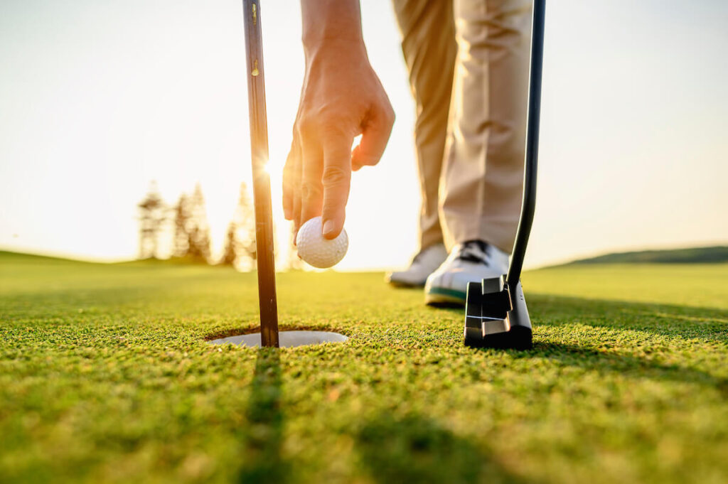 Golfer picking up a golf ball