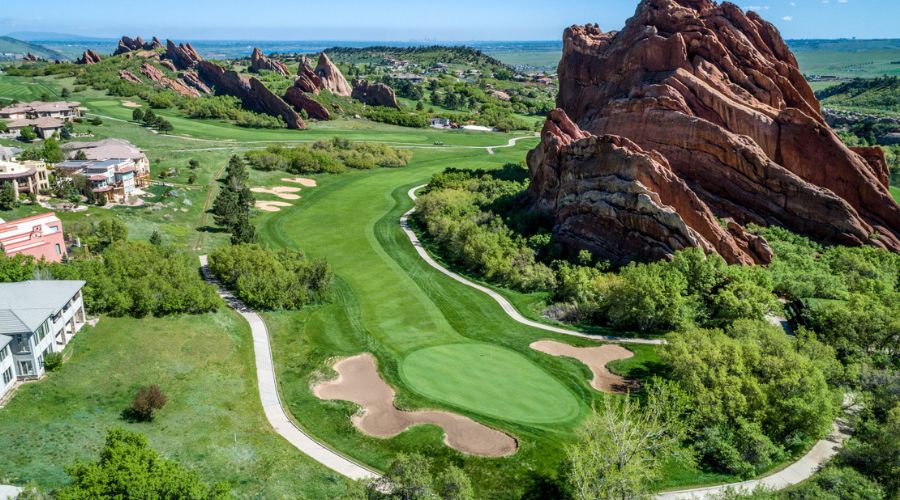 A scenic golf course with lush greenery and striking red rock formations, showcasing one of the best golf courses in Denver.