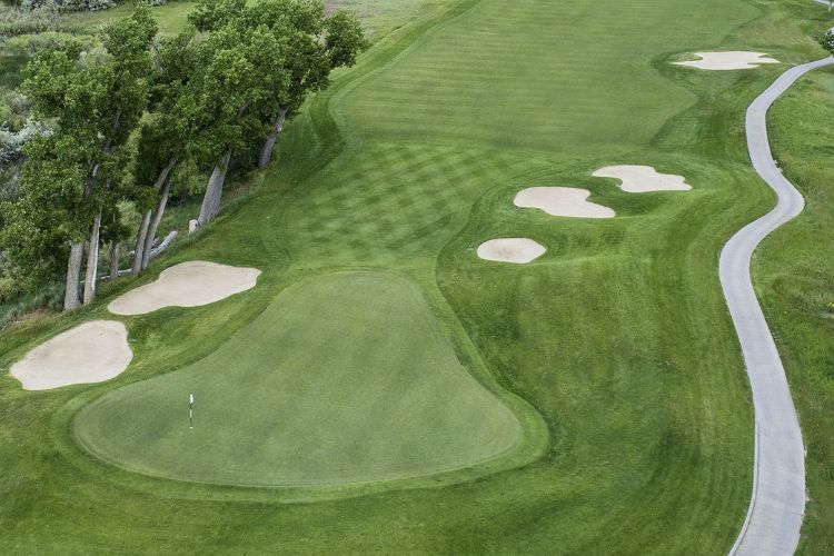 A pristine fairway and green with surrounding sand bunkers at Green Valley Ranch Golf Club, a top golfing destination in Denver.