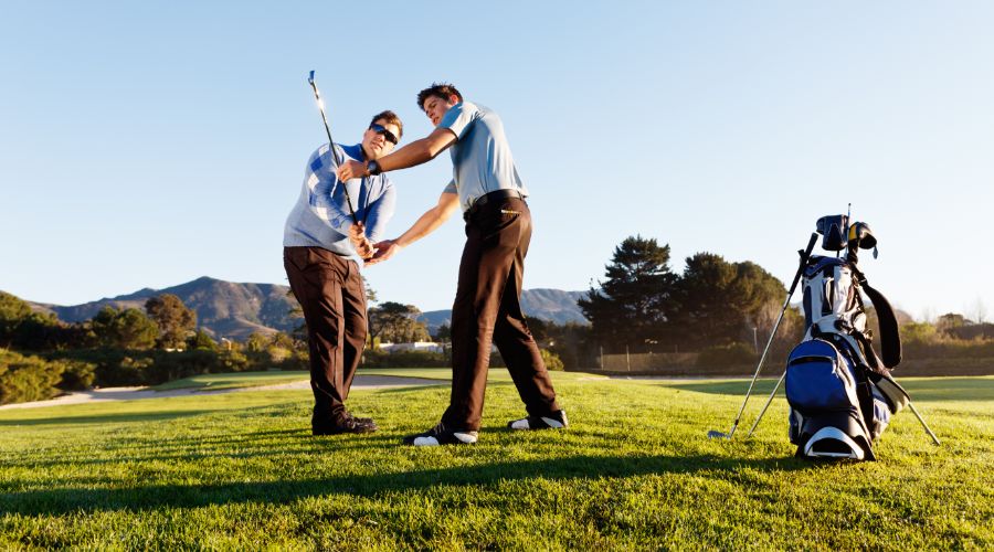 Golf coach helping golfer with backswing.