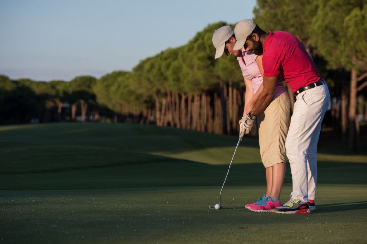 Coach helping golfer with putt