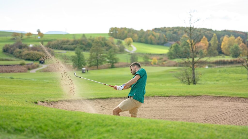 Golfer hitting an explosion shot from a sand bunker