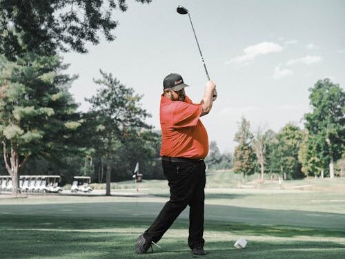 Male golfer swinging a club on a sunny golf course