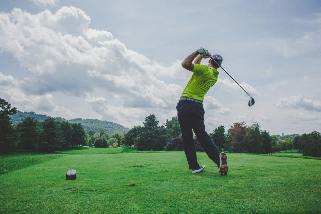 Male golfer in mid-swing with driver on golf course